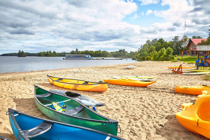 Colourful kayaks on sandy beach at OWL Rafting on the Ottawa River