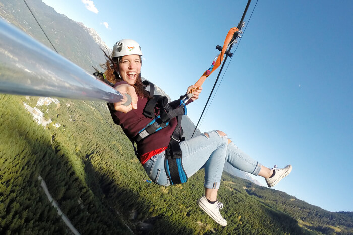 Happy girl on a zipline above trees