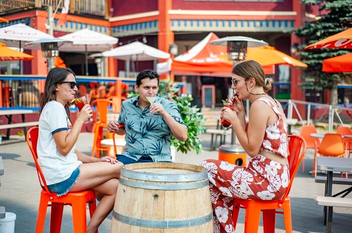 Three people enjoying drinks around a wine barrel