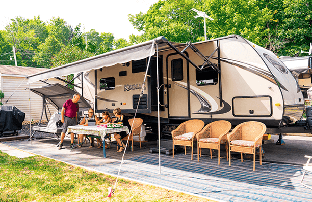 Camping trailer with people around picnic table