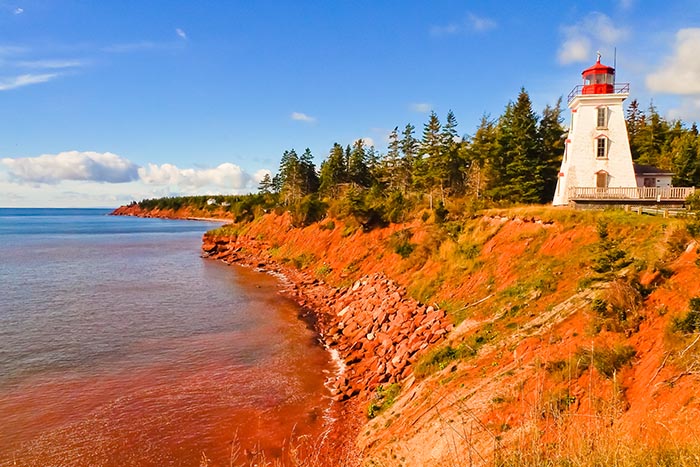 Lighthouse on a red rocky shore in Prince Edward Island