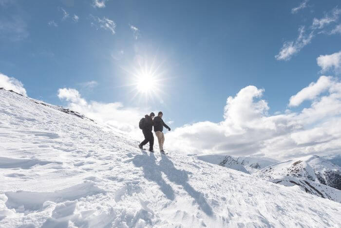 Two people walking on mountain snow on a sunny day