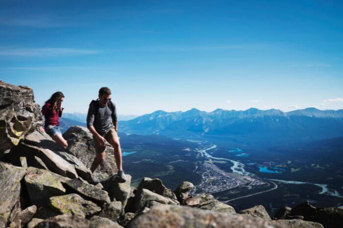 Two people on a rock looking out at alpine scenery