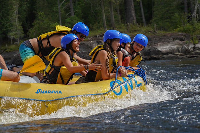 Group of people in yellow raft wearing blue helmets