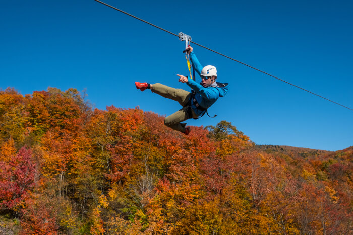 Man on zipline holding on with one hand