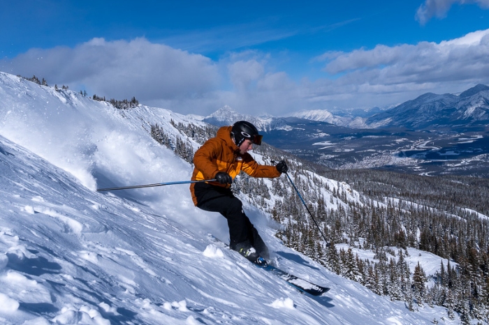 skier in orange skiing down mountain side