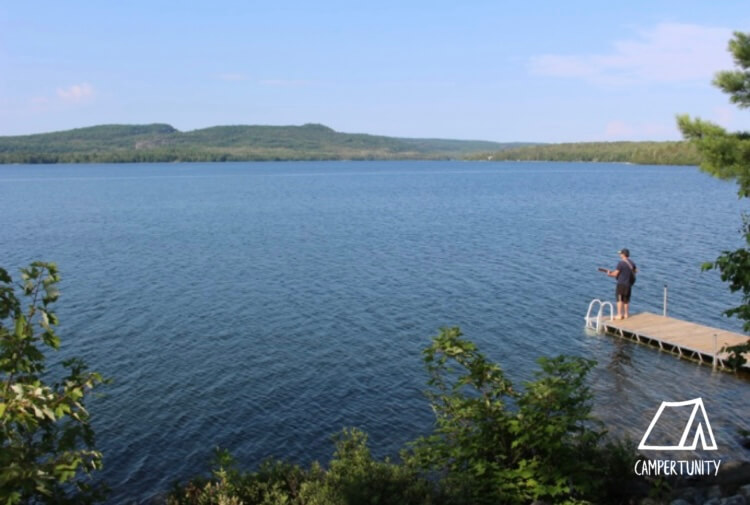 Man fishing on a lake with hills in background