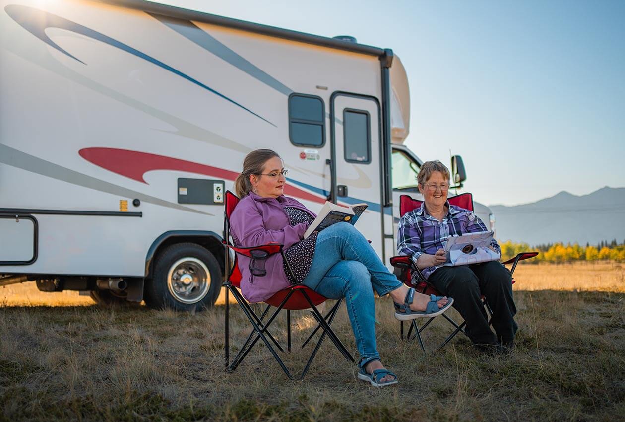 Two women relaxing outside of a CanaDream Super Van Camper