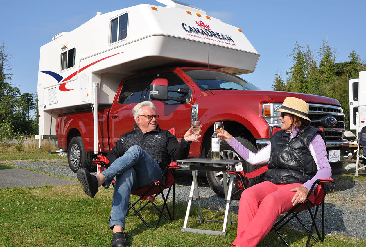 Senior couple drinking wine in front of CanaDream RV truck and camper