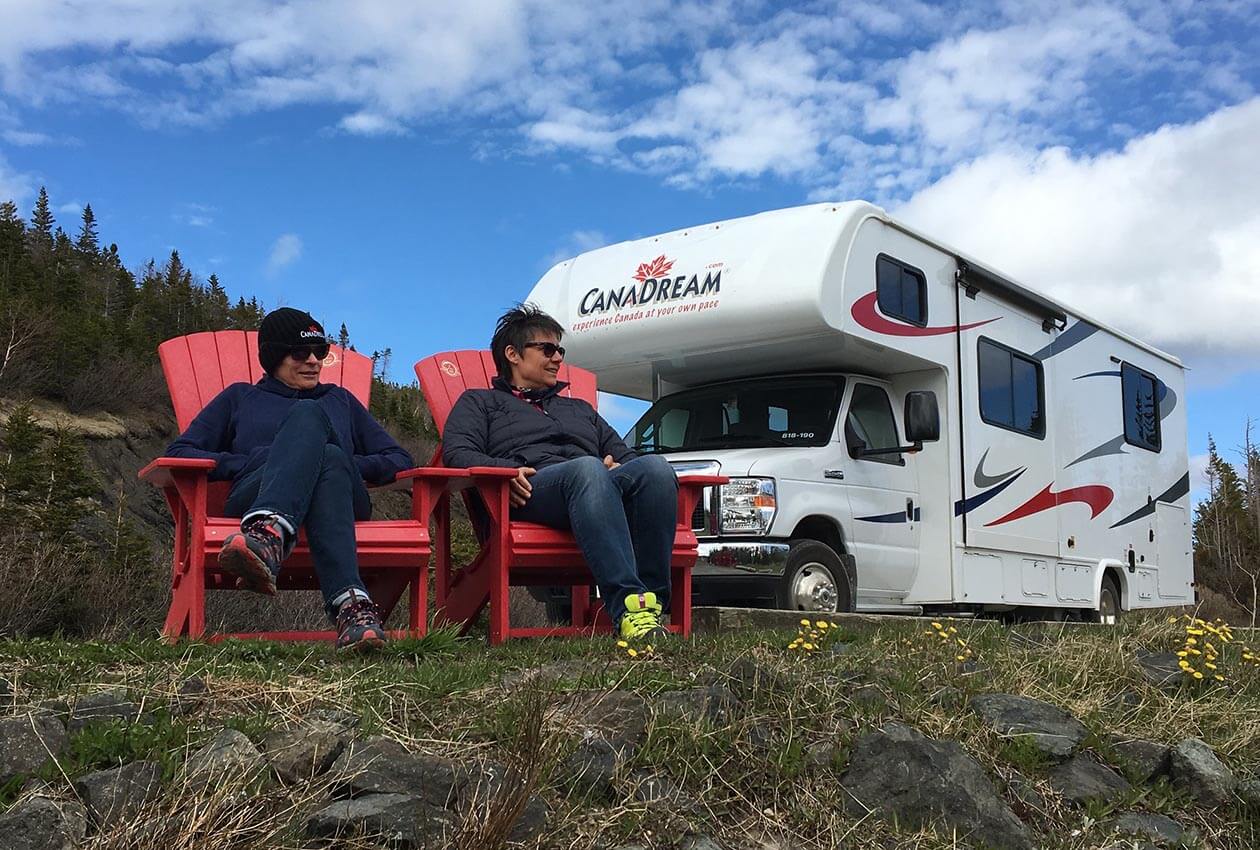 CanaDream Maxi Motorhome and two people admiring the view from the Parks Canada Red Chairs