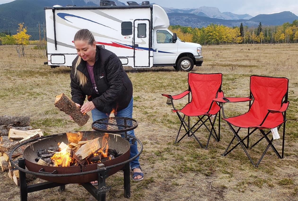 Lady adding firewood to a campfire