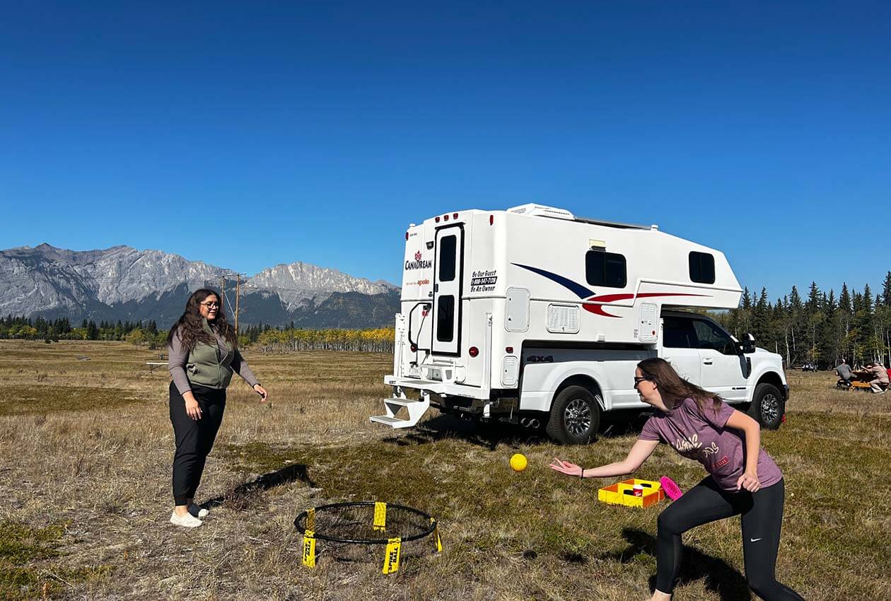 Friends playing spikeball with truck camper in background